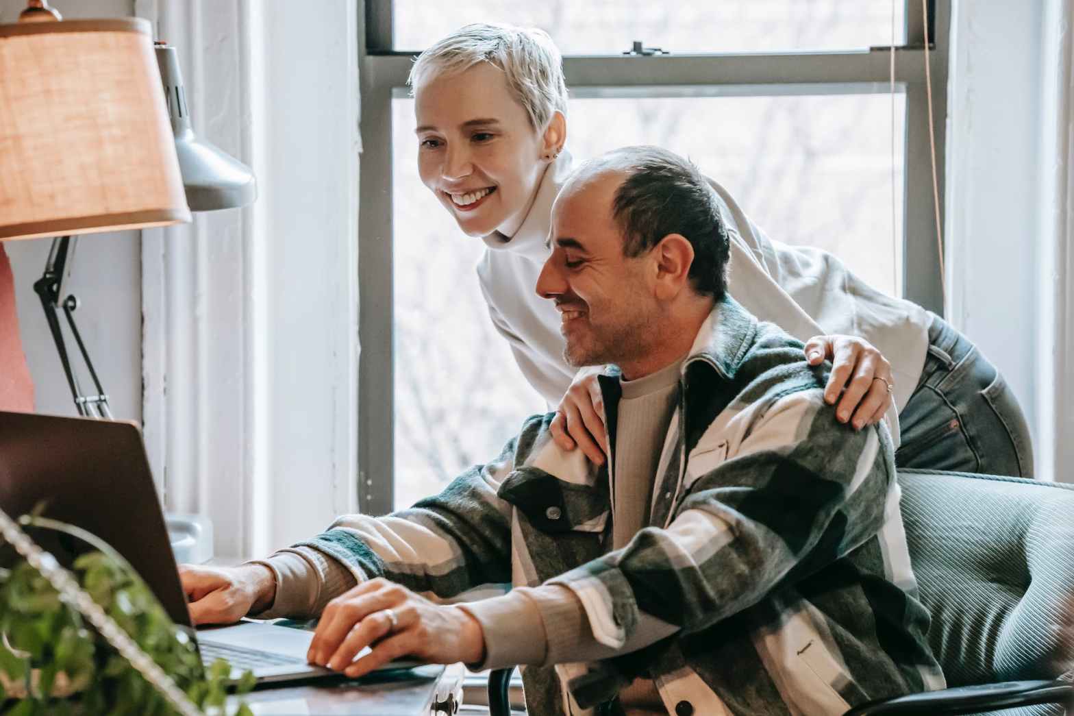 cheerful couple working together with laptop